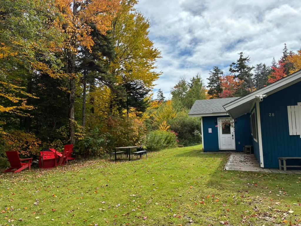 Red Adirondack chairs and a picnic table beside Ahmeek